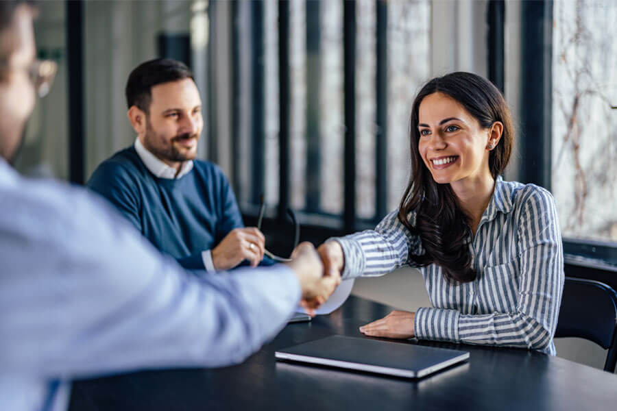 Woman and man shaking hands in an office environment.