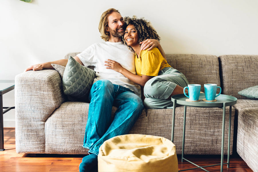 Male and female couple sitting on couch in cosy looking house.
